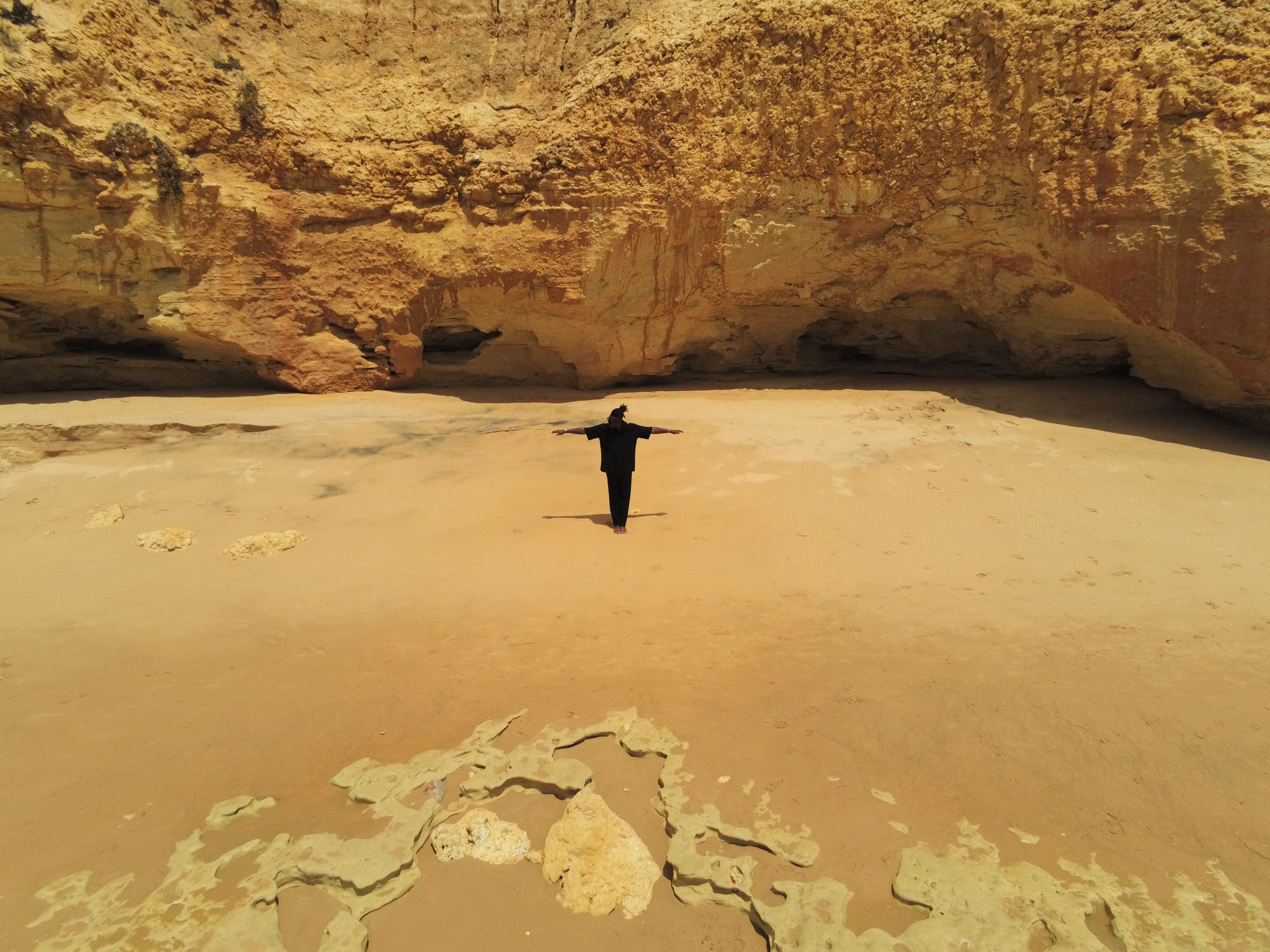 Walking along a beach beneath golden cliffs